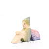 Eric & Albert wooden toy fairy in green sitting on the ground with pinky purple wings | © Conscious Craft